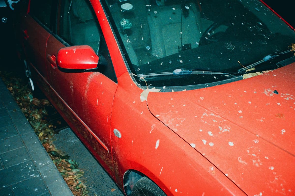 A dirty red car before a ShineCrew wash